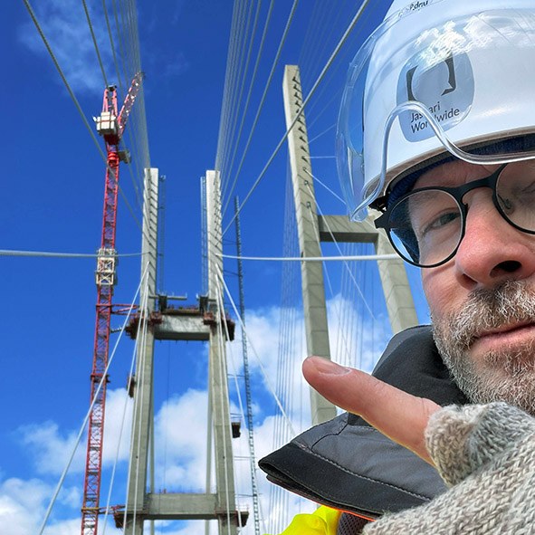 Jaakko Jaskari kypärä päässä siltatyömaalla, taustalla sillan pylonit ja nosturi